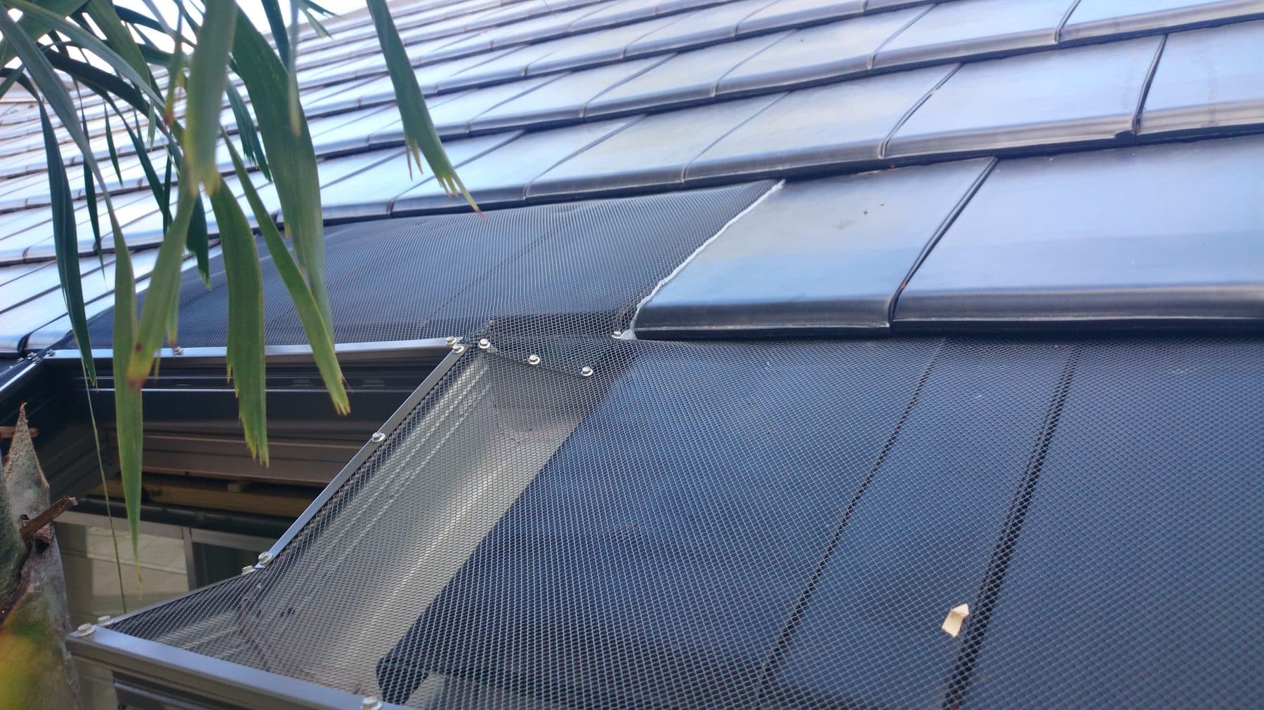 Gutter guard fitted neatly around a rooftop solar panel on a tiled roof