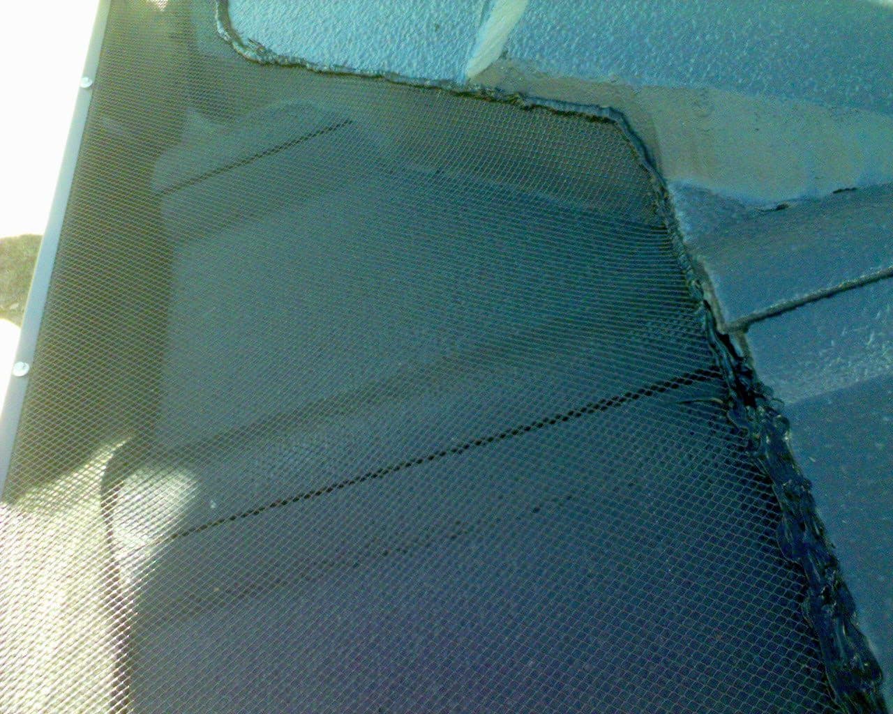 Gutter guard mesh sealed into the corner of a tile roof, where the capping stops it tucking under the tiles